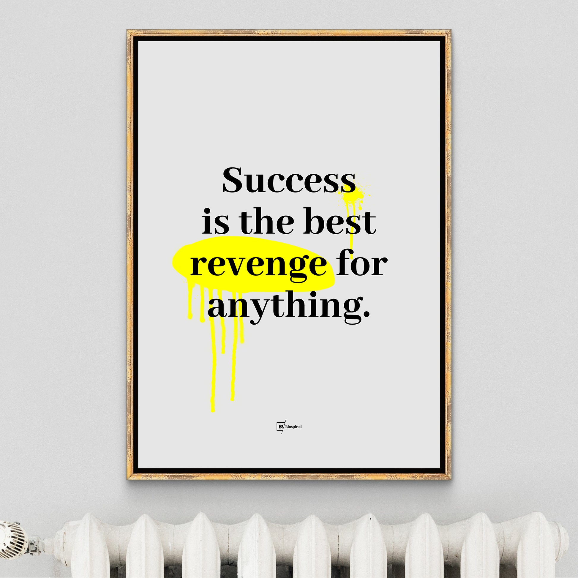 The Success Is the Best Revenge for Anything art print framed in a simple, antique golden frame above a radiator, complementing the warm, minimalist decor of the room.